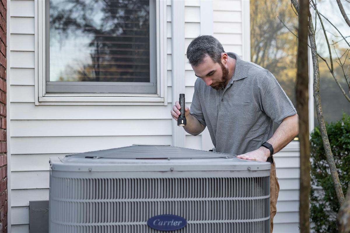 HVAC technician inspecting an outdoor air conditioning unit